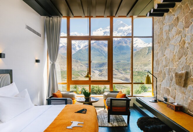 This guest room at Shinta Mani Mustang in Nepal has stone walls and floor to ceiling windows facing alpine views.