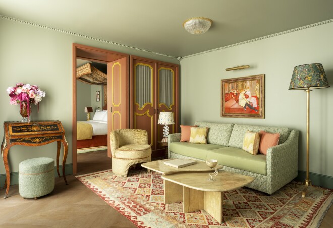 This guest room at Le Grand Mazarin features green furnishings, carved doors, and fresh flowers.